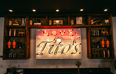 Illuminated sign features the Tito's Handmade Vodka logo alongside Love, Tito's branding in the retail store in Austin, Texas