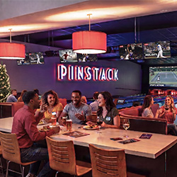 Groups of people eat and drink at tables inside the dining and bowling area at PINSTACK in Austin, Texas