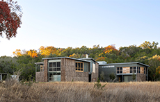 Two-story buildings in a field along a tree line at Campsite at Shield Ranch in Dripping Springs, Texas, near Austin