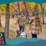 View from behind of a man, woman and child walking a path through trees with orange leaves, with overlay text that reads: Hello North Dakota