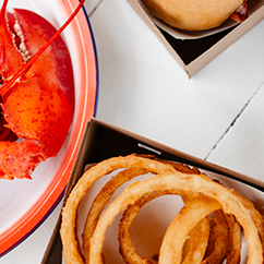 White picnic table with lobster, clams and onion rings.