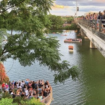 A crowd watches bats fly out from underneath the Congress Avenue Bridge at dusk